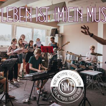 Das Bild zeigt eine Musikprobe, bei der eine Gruppe junger Menschen musiziert. Einige spielen Instrumente wie Flöte, Keyboard, Bassgitarre und Schlagzeug, während andere singen. Ein junger Mann im Vordergrund dirigiert die Gruppe. Im Hintergrund sind große Fenster zu sehen, die viel Tageslicht hereinlassen. Der Schriftzug "DAS LEBEN IST (M)EIN MUSICAL" ist in großen, dekorativen Buchstaben am oberen Rand des Bildes platziert.
