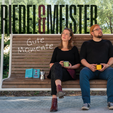 Ein Mann und eine Frau auf einer Schaukelbank, halten Tassen und schauen in die Ferne. Neben ihnen steht eine Gitarre und der Schriftzug "Gute Momente"