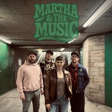 Vier Personen der Band ‚Martha & The Music‘ posieren in einem Tunnel unter einem grünen Logo mit dem Bandnamen. Sie tragen lässige Kleidung wie Lederjacken, Kapuzenpulli und Jeans.
