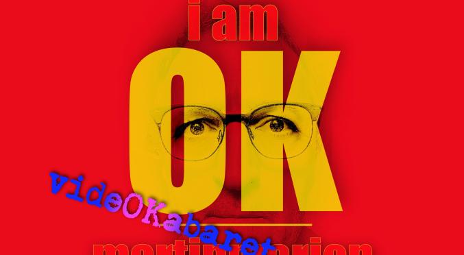 Porträt mit Brille, überlagert von gelben Buchstaben ‚I AM OK‘ und blauen Schriftzügen ‚Video Kabaret Martinmarion‘ auf rotem Hintergrund.