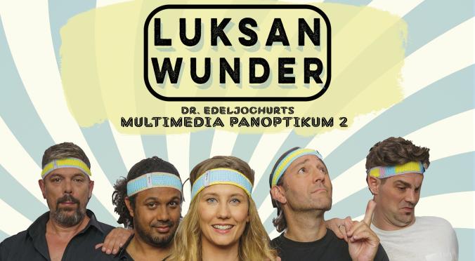 Vier lächelnde Personen mit Stirnbändern posieren vor pastellfarbenem Hintergrund mit Sonnenstrahlen; Text ‚Luksan Wunder – Das neue Comedy Live Programm, Deutscher Kleinkunstpreis 2023‘.