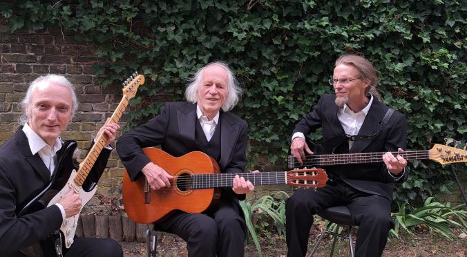 Drei Männer sitzend im Grünen mit Gitarren