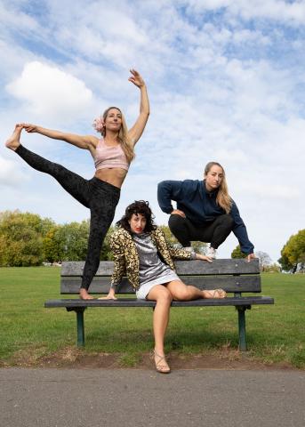 Das Bild zeigt drei Frauen auf einer Parkbank in dynamischen Posen. Eine führt eine Yoga-Bewegung aus, eine sitzt lässig, und die dritte posiert athletisch.