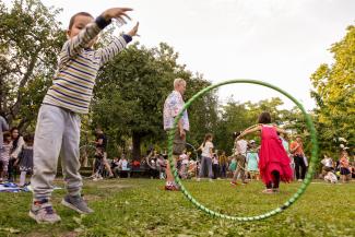 Kinder spielen auf einer Wiese mit Hula-Hoop-Reifen